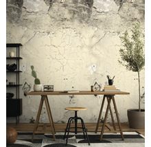 Vliesbehang met betonlook en barstjes in een werkkamer met een houten bureau, een kruk en een kamerplant.