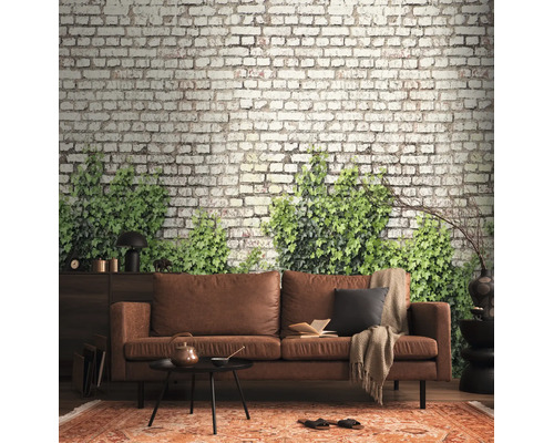 Fotobehang met bakstenen muur en groene klimop achter een bruine leren bank in een modern ingerichte woonkamer.