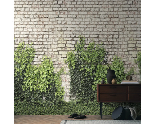 Fotobehang met bakstenen look en groene klimop achter een donker houten dressoir op een parketvloer in rustieke stijl.