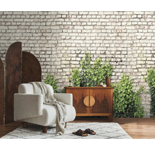 Fotobehang met baksteenlook en groene klimop in een woonkamer met fauteuil en dressoir.
