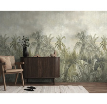 Fotobehang met tropisch jungle-motief in gedempte kleuren, palmbomen en grote bladeren in vintage stijl achter een houten dressoir.