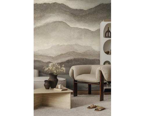 Fotobehang met abstract berglandschap in natuurtinten in een modern ingerichte woonkamer met fauteuil en salontafel.