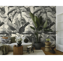 Moderne woonkamer met zwart-wit jungle fotobehang, lichte bank, grote kamerplant en decoratieve bijzetafels.