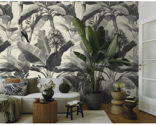 Moderne woonkamer met zwart-wit jungle fotobehang, lichte bank, grote kamerplant en decoratieve bijzetafels.