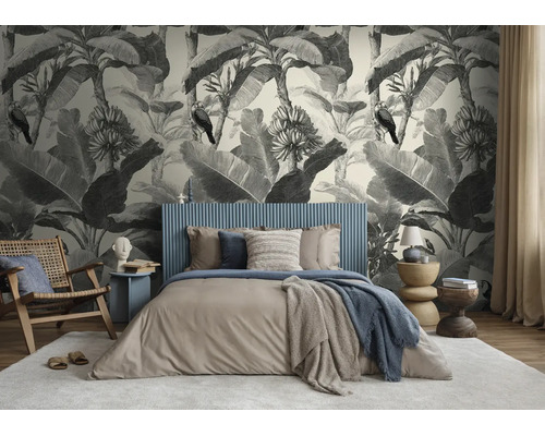 Lichte slaapkamer met botanisch fotobehang met bananenbladeren en vogels in vintage stijl achter een blauw bed.