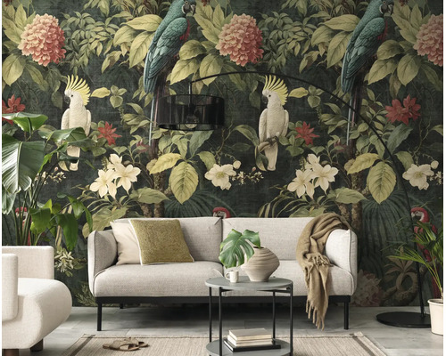 Botanisch vliesbehang met papegaaien en bloemen in een moderne woonkamer met een lichtgrijze bank en zwarte booglamp.