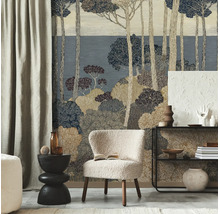 Vliesbehang met gestileerd bosmotief van dennen en struiken in blauw- en beigetinten achter een lichte fauteuil in een moderne kamer.