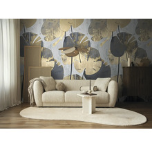 Moderne woonkamer met fotobehang met abstract bladpatroon in goud en grijs achter een lichtkleurige bank en een ovaal vloerkleed.
