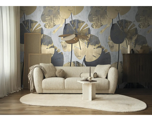 Moderne woonkamer met fotobehang met abstract bladpatroon in goud en grijs achter een lichtkleurige bank en een ovaal vloerkleed.