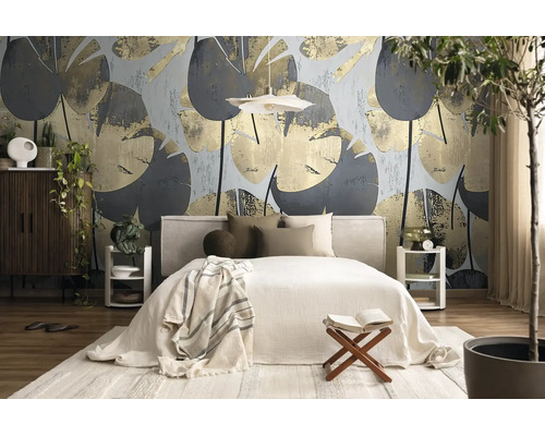 Moderne, lichte slaapkamer met behang met groot bladpatroon, gestoffeerd bed, houten meubels en kamerplanten.