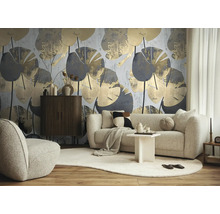 Moderne woonkamer met groot botanisch behang met grijze en gouden bladpatronen, bank, fauteuil en dressoir van donker hout.
