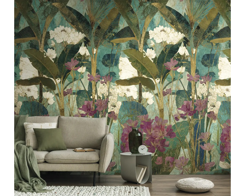 Fotobehang met tropisch motief van bananenbladeren en witte en roze bloemen achter een lichte bank in de woonkamer.