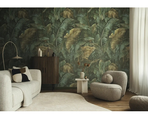 Fotobehang met grote tropische bladeren in jungle-stijl in een modern ingerichte woonkamer met lichte bank en grijze fauteuil.