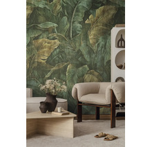 Vliesbehang met grote botanische bladeren in een modern ingerichte woonkamer met fauteuil en salontafel.