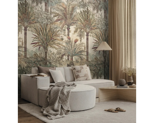 Een lichte woonkamer met een groot botanisch behang met palmbomen, een lichte modulaire bank en een houten salontafel.