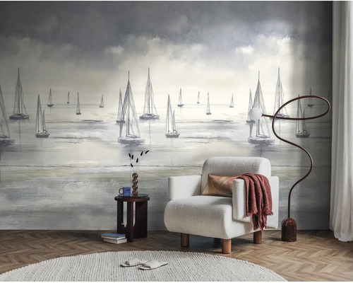 Fotobehang met zeilboten op zee in een modern ingerichte woonkamer met fauteuil, vloerlamp en vloerkleed op een parketvloer.