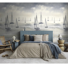 Slaapkamer met fotobehang van zeilboten, bed met blauw geribbeld hoofdbord en beddengoed in neutrale tinten, houten stoel en moderne bijzettafels.