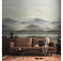 Fotobehang met mistig berglandschap in een woonkamer met bruine leren bank.