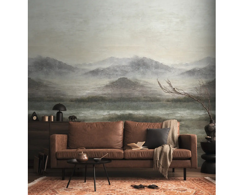 Fotobehang met mistig berglandschap in een woonkamer met bruine leren bank.