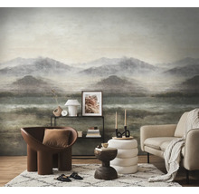 Wandvullend fotobehang met bergmotief in een woonkamer met fauteuil, bank, vloerkleed en decoratie op een plank.