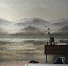 Fotobehang met mistig berglandschap in zachte kleuren achter een houten dressoir in een minimalistisch ingerichte kamer.