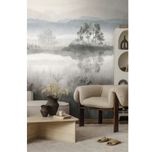 Moderne, lichte woonkamer met vliesfotobehang met mistig berglandschap, een fauteuil van stof en een salontafel van hout.