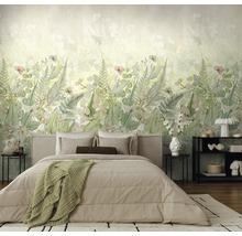 Moderne slaapkamer met botanisch fotobehang, blad- en varenmotieven in zachte groentinten achter een bed met beige beddengoed.