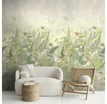 Fotobehang met botanisch varen- en bloemenpatroon in een lichte woonkamer met witte bank en houten stoel.
