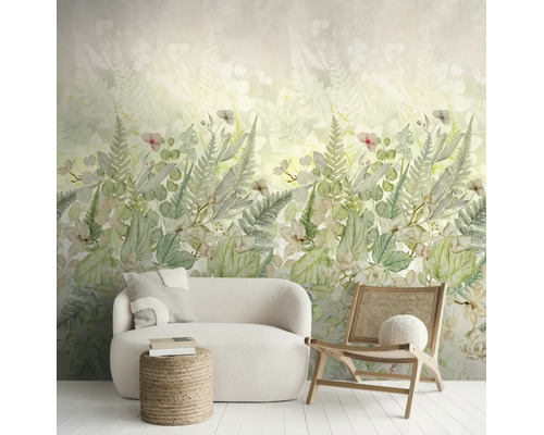 Fotobehang met botanisch varen- en bloemenpatroon in een lichte woonkamer met witte bank en houten stoel.