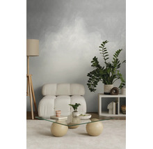 Moderne woonkamer met modulaire fauteuil, glazen salontafel op bolvormige poten, houten driepoot vloerlamp en getextureerd behang.