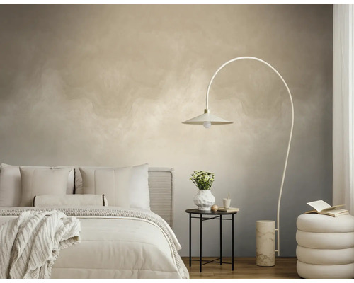 Slaapkamer met licht behang met wolkeneffect, een booglamp, een bed met wit beddengoed en een kleine bijzettafel.