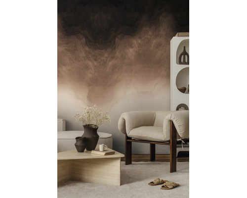 Vliesbehang met abstract, gemarmerd patroon in aardetinten, gecombineerd met een moderne fauteuil en stenen tafel in een lichte woonruimte.
