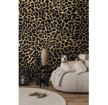 Woonkamer met vliesbehang met luipaardprint, een lichte fauteuil, zwarte bijzetstafel en een decoratieve draadlantaarn.