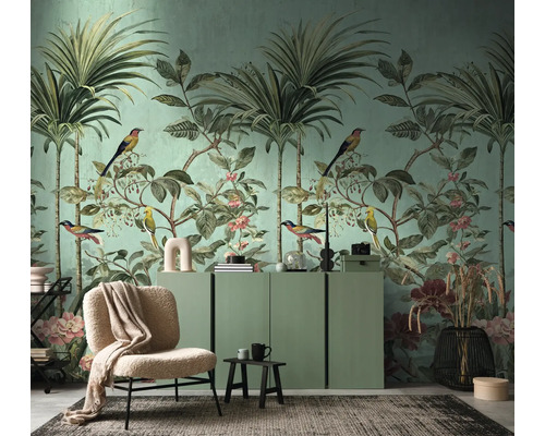 Woonkamer met tropisch behang met palmbomen, vogels en bloemen, een groen dressoir, een beige fauteuil en een vloerkleed.