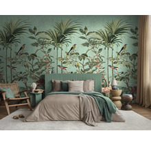 Slaapkamer met tropisch fotobehang met palmen en vogels, een groen geribbeld hoofdbord en houten fauteuil op een wit tapijt.