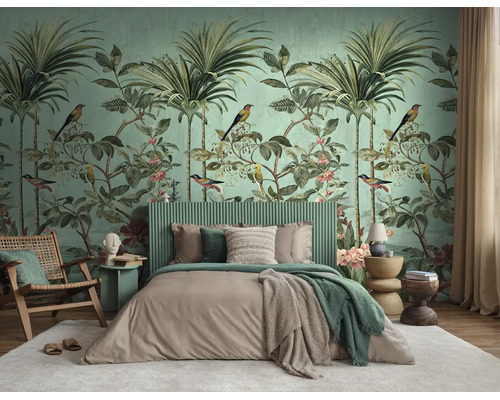 Slaapkamer met tropisch fotobehang met palmen en vogels, een groen geribbeld hoofdbord en houten fauteuil op een wit tapijt.