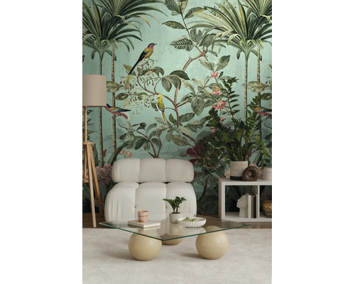 Tropisch fotobehang met palmen, vogels en bloemen in een woonkamer met witte fauteuil en glazen tafel.