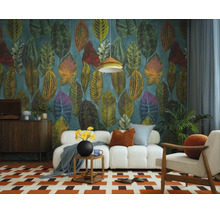 Vliesbehang met grote, kleurrijke bladeren in een modern ingerichte woonkamer met een witte bank en een gedessineerd vloerkleed.
