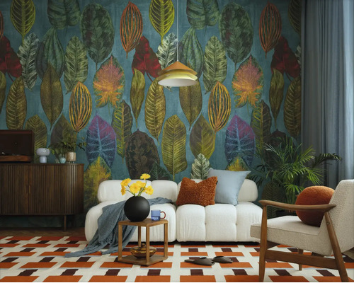 Vliesbehang met grote, kleurrijke bladeren in een modern ingerichte woonkamer met een witte bank en een gedessineerd vloerkleed.