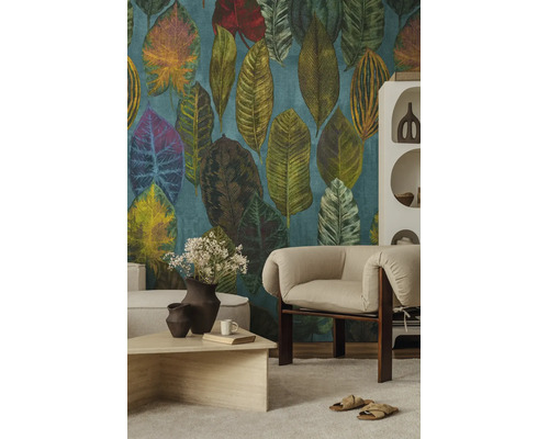 Vliesbehang met groot patroon van tropische bladeren in een modern ingerichte woonkamer met een beige fauteuil en salontafel.