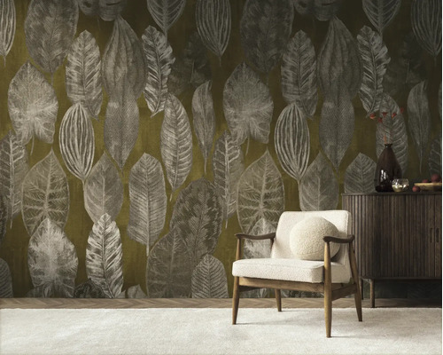 Vliesbehang met groot bladmotief in een woonkamer met houten fauteuil en een dressoir.