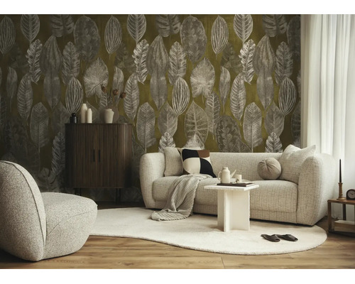 Woonkamer met behang met bladmotief, lichte stoffen bank, donker houten kastje en tapijt op parket.