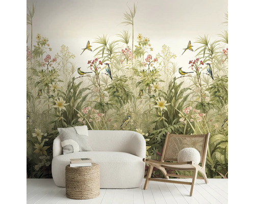 Vliesbehang met botanisch motief van tropische planten, bloemen en vogels, in een lichte kamer met witte bank en houten stoel.