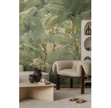 Vliesbehang met bananenbladmotief in vintage stijl in een lichte, modern ingerichte woonkamer met fauteuil en salontafel.