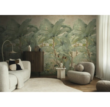 Moderne woonkamer met een groot fotobehang van bananenbladeren, een lichte bank, een fauteuil en een donker dressoir.