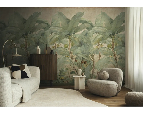 Moderne woonkamer met een groot fotobehang van bananenbladeren, een lichte bank, een fauteuil en een donker dressoir.