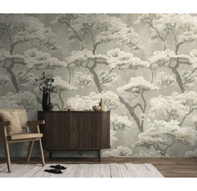 Vliesbehang met Japans boompatroon in een woonkamer achter een houten dressoir en een fauteuil.