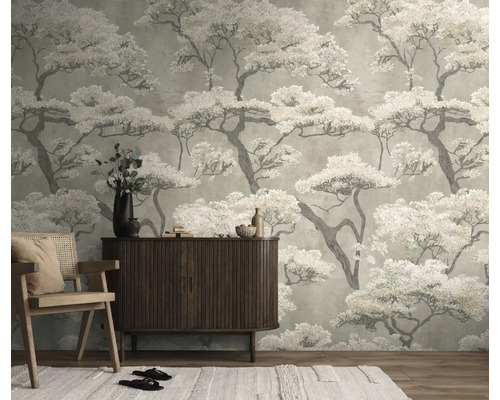 Vliesbehang met Japans boompatroon in een woonkamer achter een houten dressoir en een fauteuil.