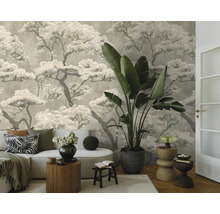 Vliesbehang met boommotief in een modern ingerichte woonkamer met een lichte bank, een kamerplant en houten meubels.