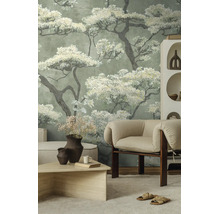 Fotobehang met grote bloesembomen in een lichte woonkamer met beige fauteuil en houten tafel.